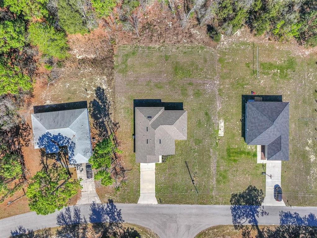 An aerial view shows three houses with driveways along a road surrounded by wooded land — 15062 SW 63RD COURT ROAD, OCALA, FL