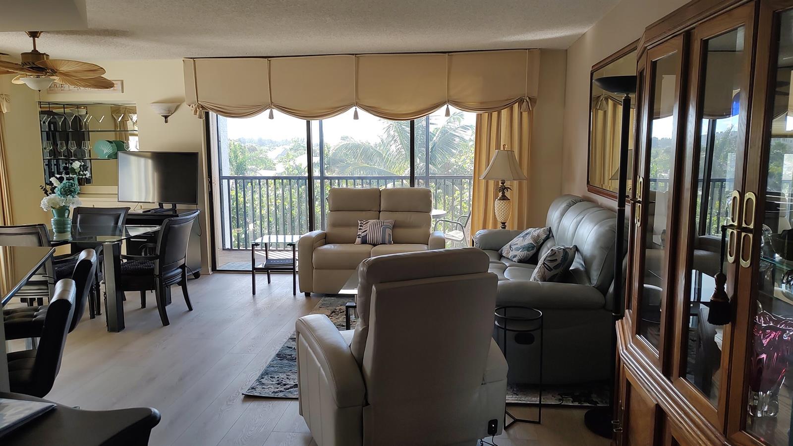 A living and dining area with light wood floors, neutral furniture, and a balcony view — 1605 S Us Highway 1 # F401, Jupiter FL 33477, JUPITER, FL