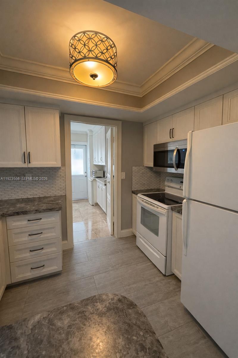 A kitchen features white cabinets, stainless steel appliances, gray countertops, and a patterned ceiling light — 4208 NW 47th Ct, Tamarac FL 33319, TAMARAC, FL