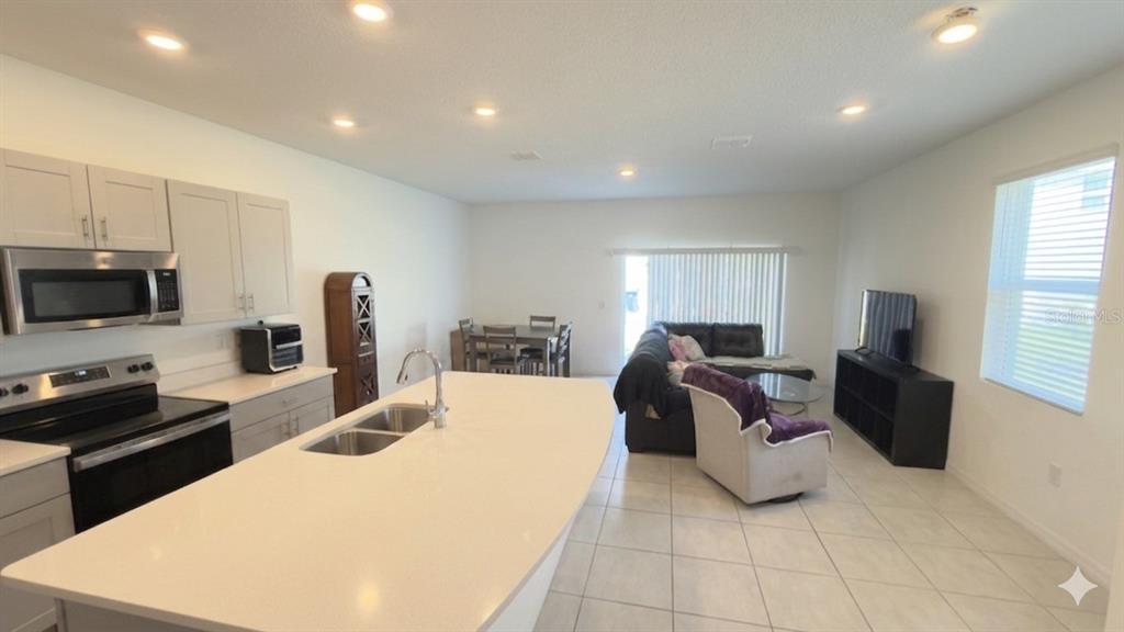 An open-concept kitchen with a large island overlooks a living and dining area — 2994 CANARY AVENUE, DAVENPORT, FL
