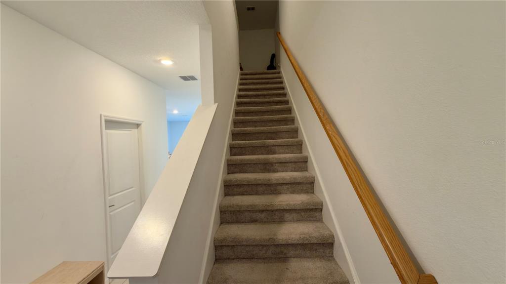 A carpeted staircase with a wooden handrail leads to an upper level — 2994 CANARY AVENUE, DAVENPORT, FL