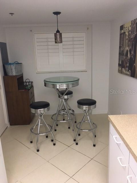 A small dining area features a glass-topped bistro table with three chrome bar stools — 9510 HARBOR GREENS WAY UNIT 501, SEMINOLE, FL