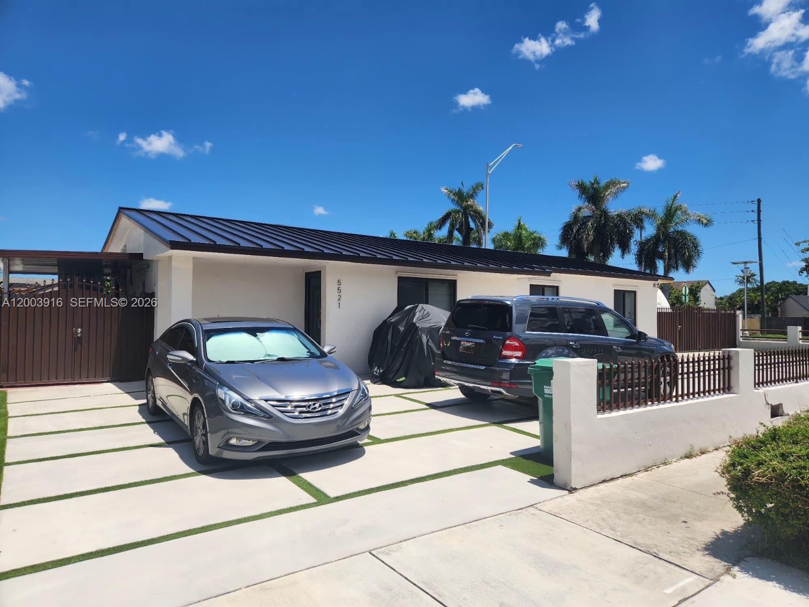 A single-story house with a dark metal roof and a paved driveway with two cars — 5521 SW 132nd Ave, Miami FL 33175, MIAMI, FL