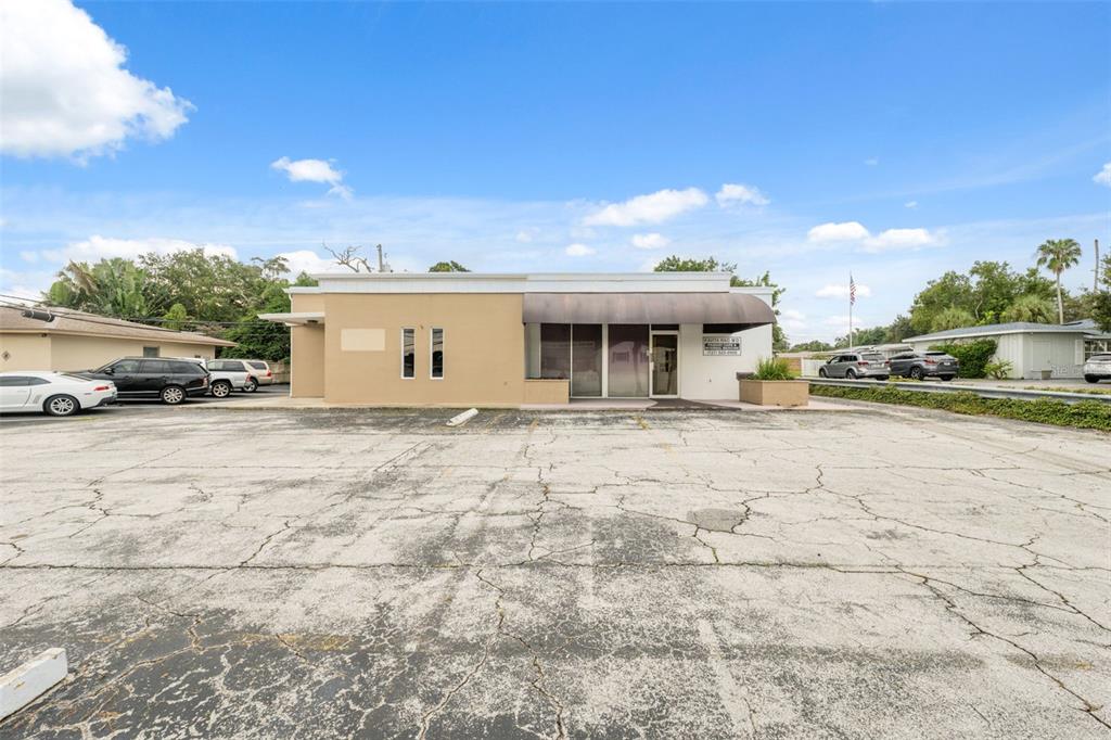 A single-story commercial building with a large, cracked asphalt parking lot in front — 2101 INDIAN ROCKS ROAD S, LARGO, FL