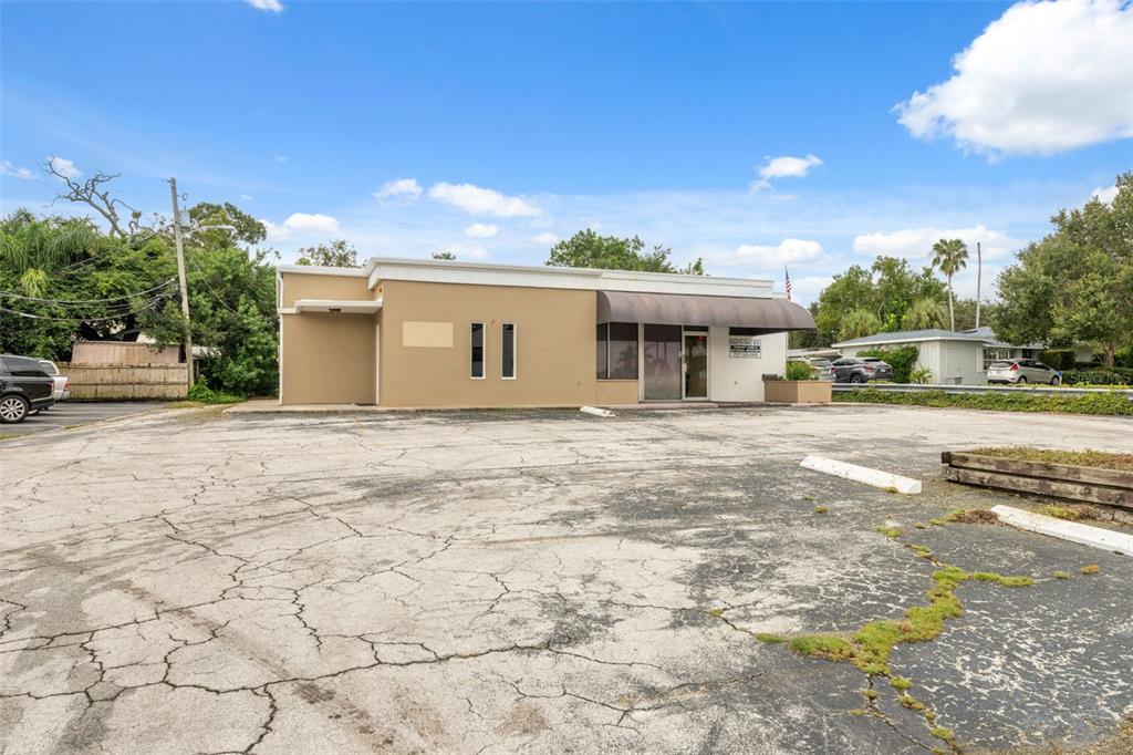 A single-story commercial building with a large, cracked asphalt parking lot in front — 2101 INDIAN ROCKS ROAD S, LARGO, FL