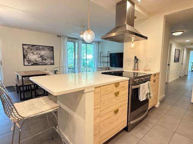 A kitchen features light wood cabinets, a white quartz island, and a stainless steel range hood — 1717 NW 23RD AVENUE UNIT GA, GAINESVILLE, FL