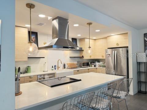 A modern kitchen features light wood cabinets, a large white island, and stainless steel appliances — 1717 NW 23RD AVENUE UNIT GA, GAINESVILLE, FL