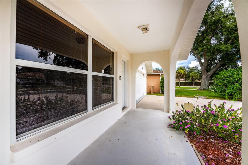 A covered front porch with a large window, arched entryway, and a small garden bed — 1458 STRADA D ARGENTO, VENICE, FL