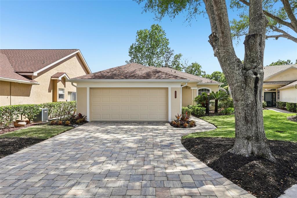 A beige house with a two-car garage and a paved driveway under a clear sky — 1036 PADDINGTON TERRACE, LAKE MARY, FL