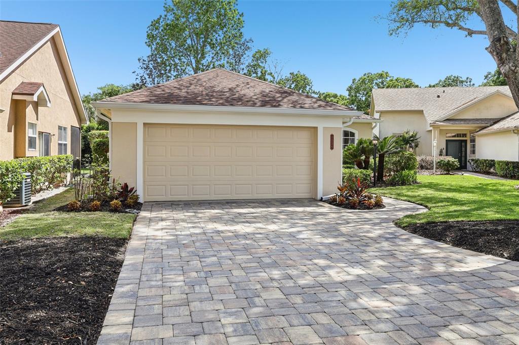 A detached garage with a tan door and a paved driveway sits between two houses — 1036 PADDINGTON TERRACE, LAKE MARY, FL