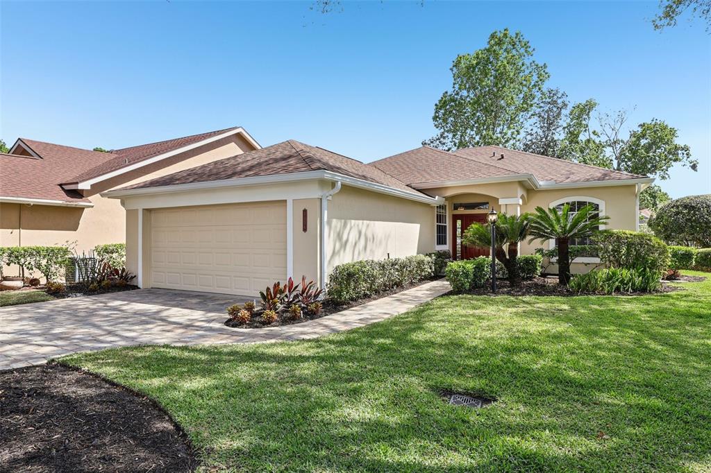 A single-story house with a beige stucco exterior, a two-car garage, and a landscaped lawn — 1036 PADDINGTON TERRACE, LAKE MARY, FL