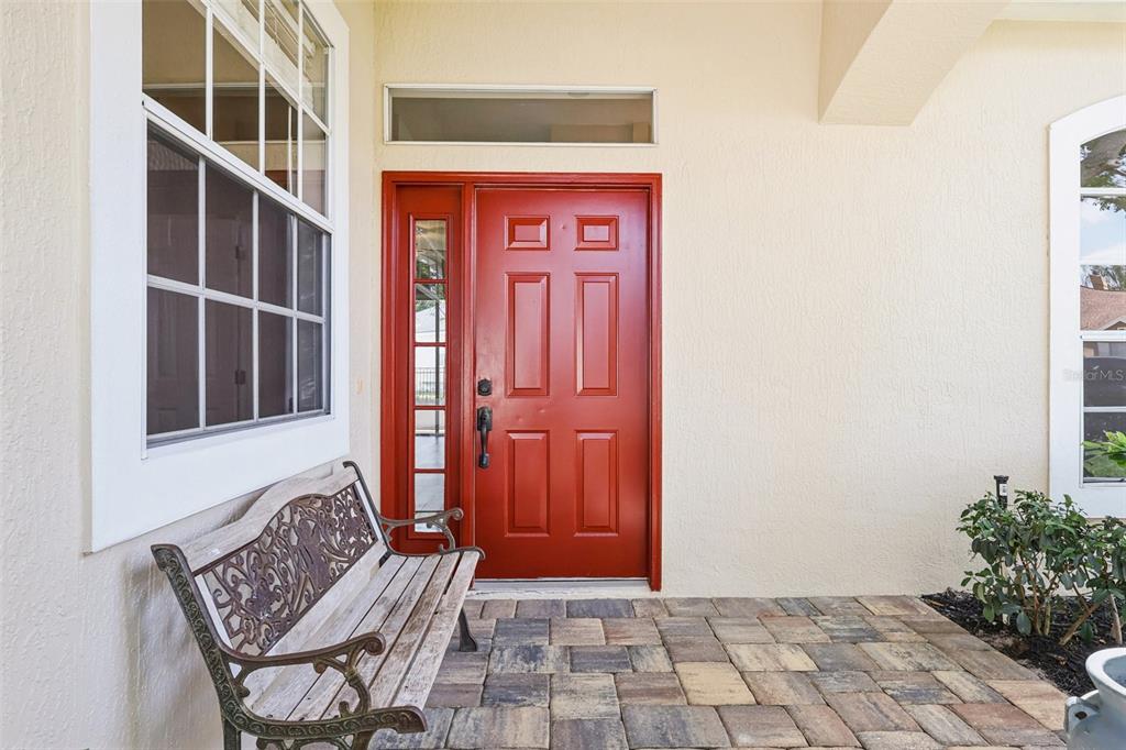 A red front door with a side light and transom window sits on a paved porch — 1036 PADDINGTON TERRACE, LAKE MARY, FL