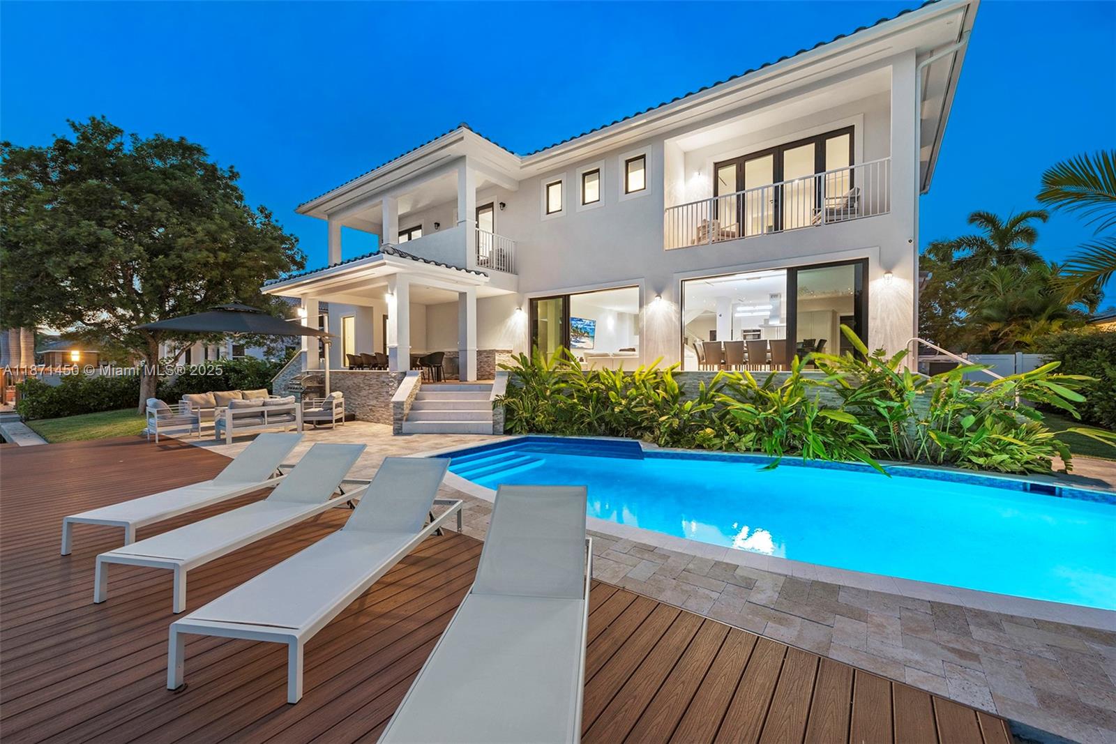 A two-story house with a pool, wooden deck, and lounge chairs at dusk — 850 Washington St, Hollywood FL 33019, HOLLYWOOD, FL