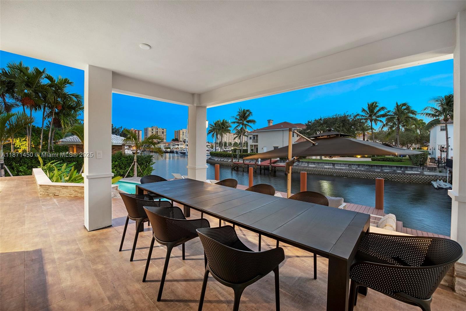 A covered patio features a long dining table overlooking a canal and swimming pool — 850 Washington St, Hollywood FL 33019, HOLLYWOOD, FL