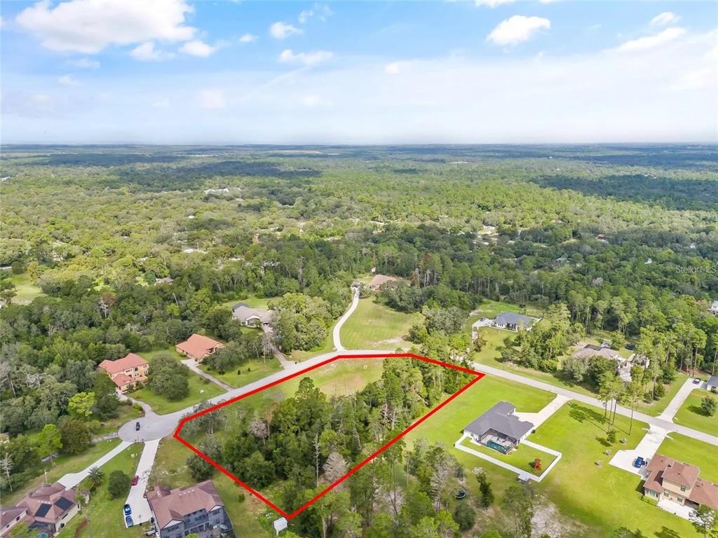 An aerial view shows a vacant, partially wooded residential lot outlined in red — 13615 GOPHER POND CT, HUDSON, FL