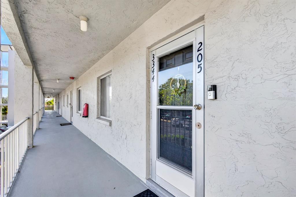 An exterior view of an apartment building hallway with a numbered glass storm door — 3344 LAKE BAYSHORE DRIVE UNIT P205, BRADENTON, FL
