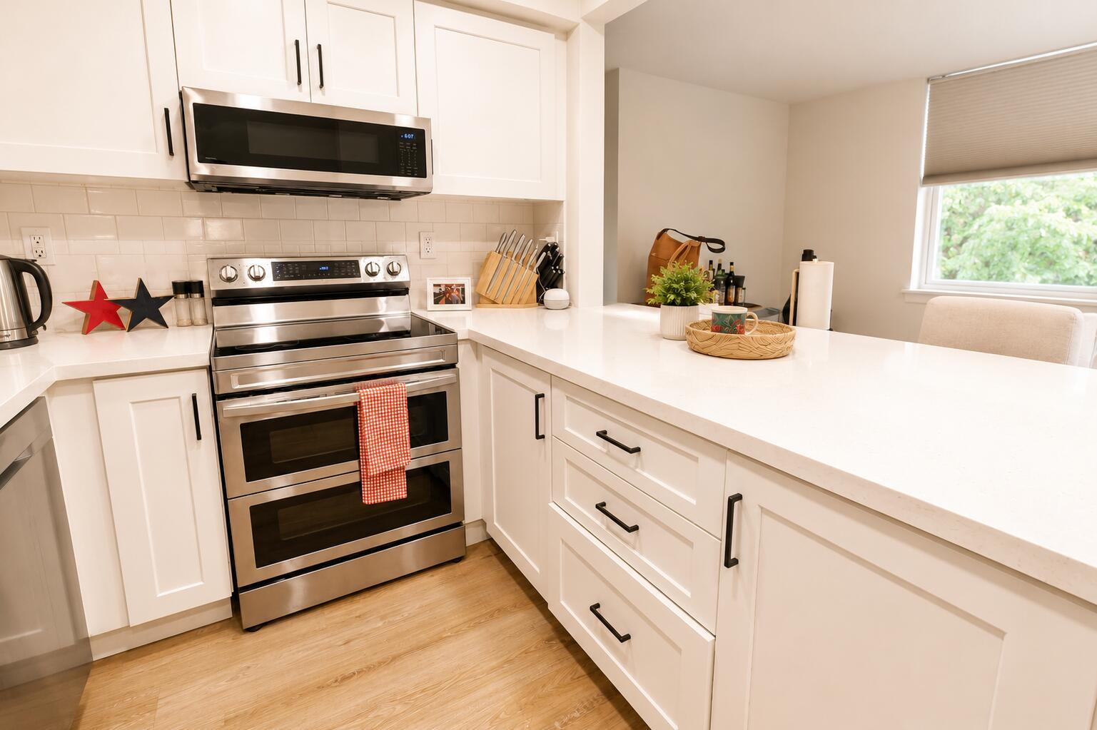 A modern kitchen features white cabinets, stainless steel appliances, and a white quartz countertop — 9491 Evergreen Place # 307, Davie FL 33324, DAVIE, FL