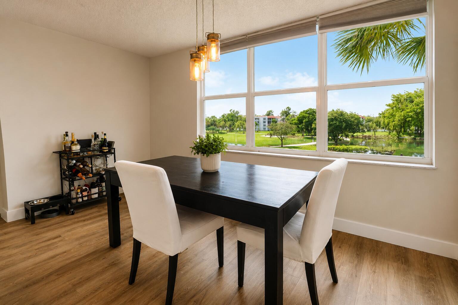 A dining room with a dark table, white chairs, a bar cart, and a window view — 9491 Evergreen Place # 307, Davie FL 33324, DAVIE, FL
