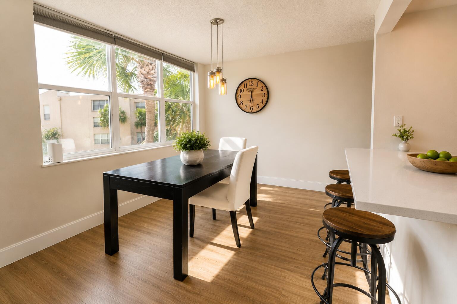 A dining area with a dark table, white chairs, pendant lights, and a wall clock — 9491 Evergreen Place # 307, Davie FL 33324, DAVIE, FL