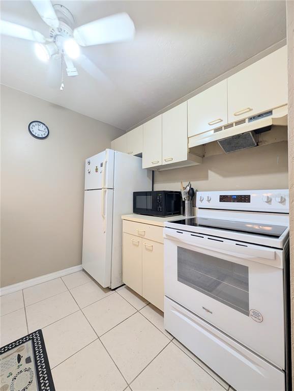 A kitchen features white appliances, beige cabinets, a ceiling fan, and light-colored floor tiles — 3609 59TH AVENUE W UNIT 3609, BRADENTON, FL