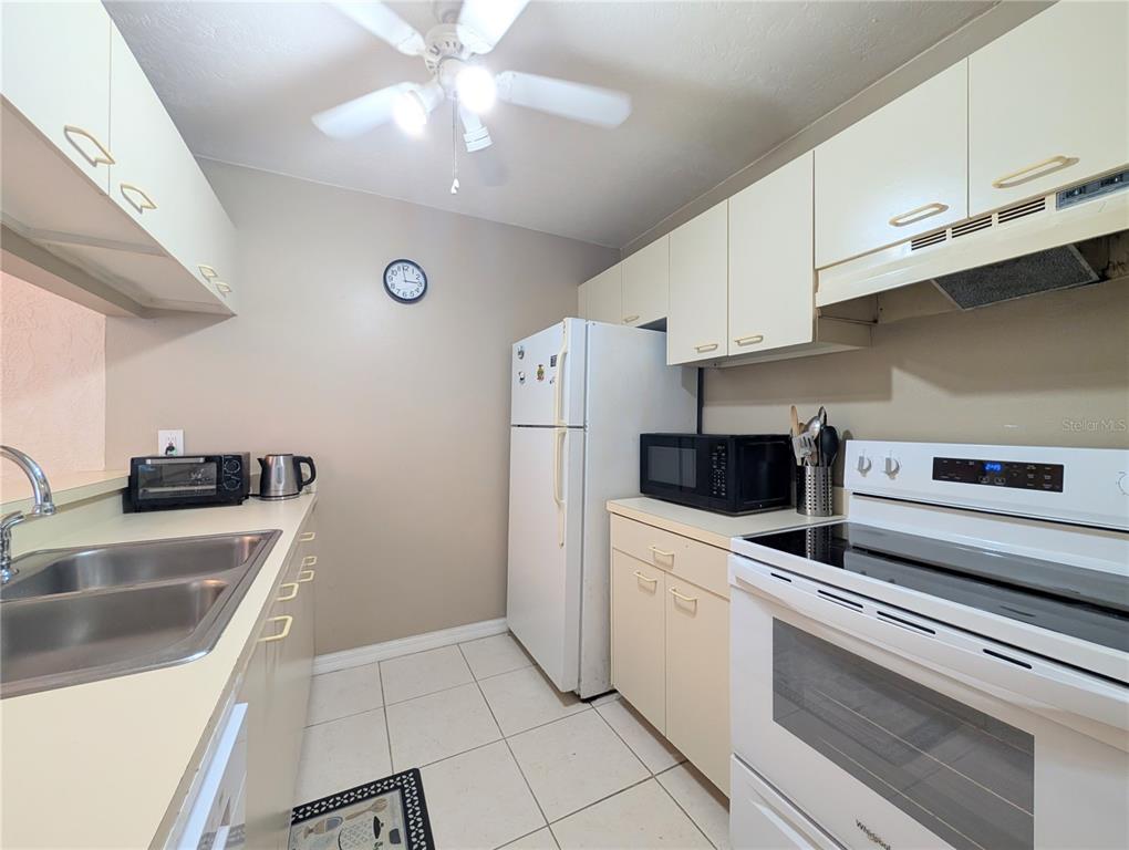 A kitchen features white cabinets, a white refrigerator, a black microwave, and a white stove — 3609 59TH AVENUE W UNIT 3609, BRADENTON, FL