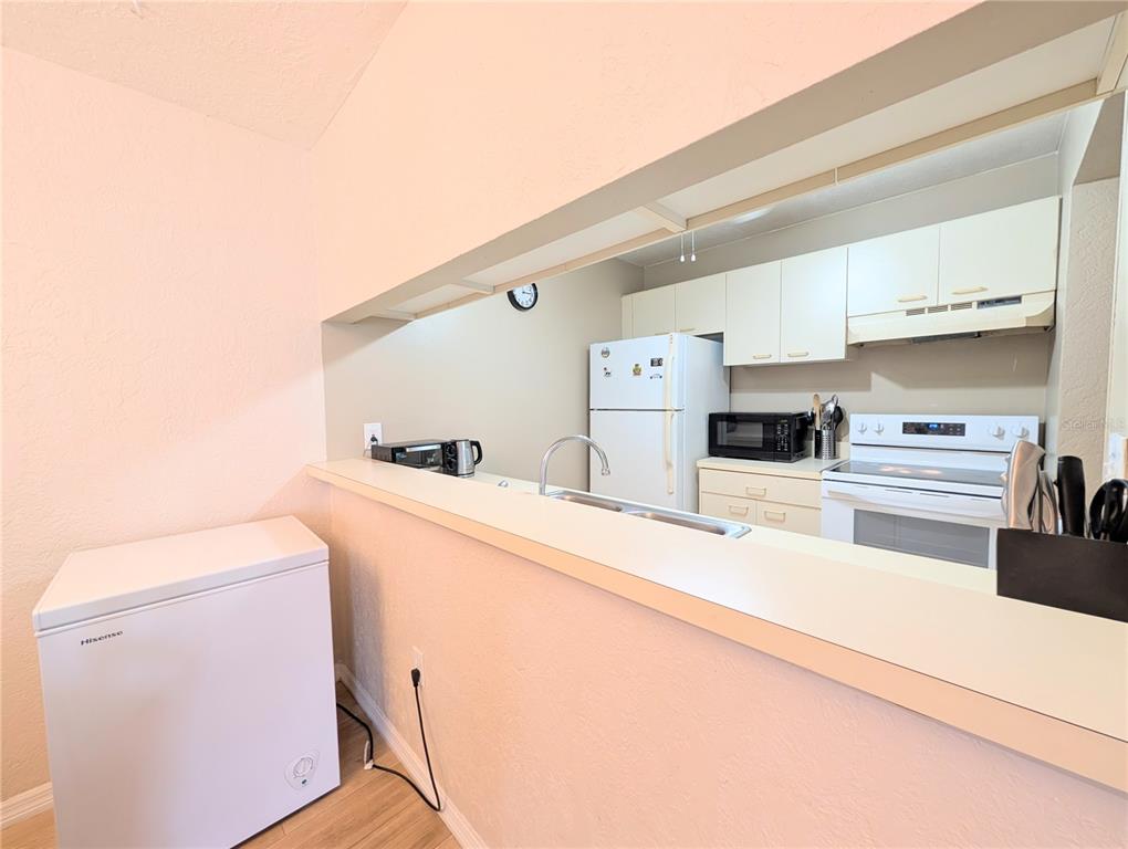 A kitchen with white cabinets and appliances is visible through a pass-through window — 3609 59TH AVENUE W UNIT 3609, BRADENTON, FL