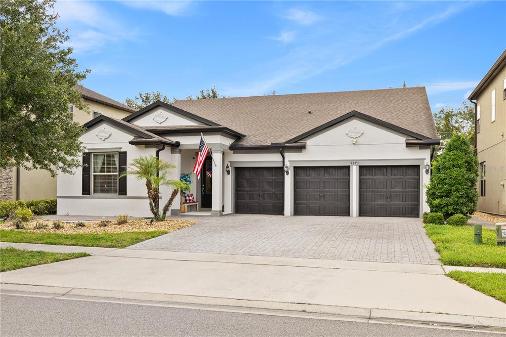 A single-story house with a white stucco exterior, a three-car garage, and a paved driveway — 9373 ROYAL ESTATES BOULEVARD, ORLANDO, FL