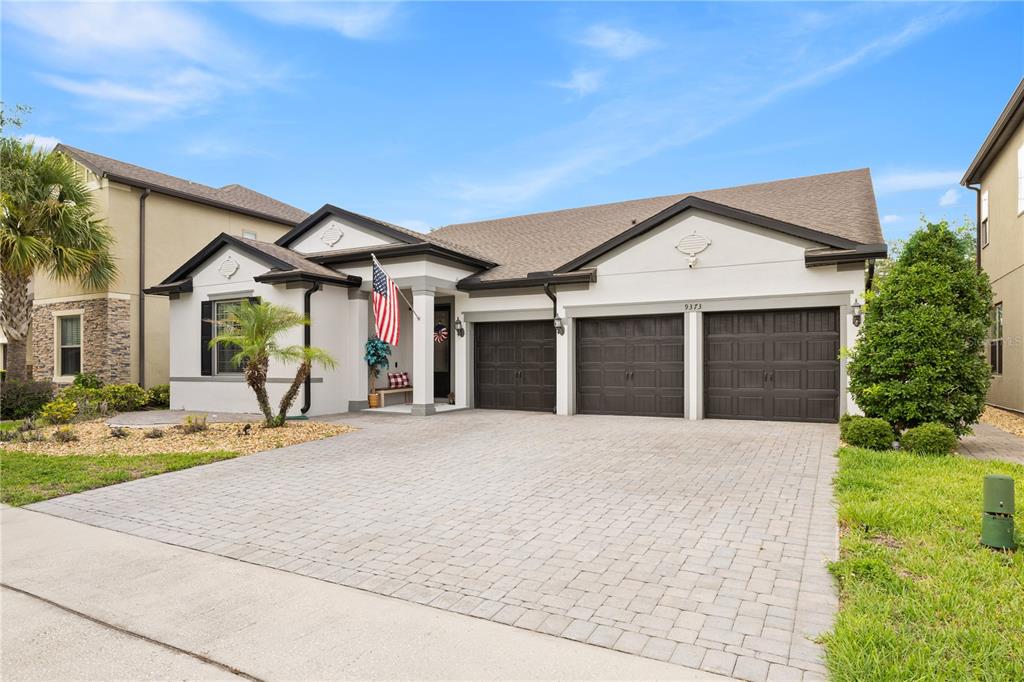A single-story house with a three-car garage and a paved driveway under a blue sky — 9373 ROYAL ESTATES BOULEVARD, ORLANDO, FL