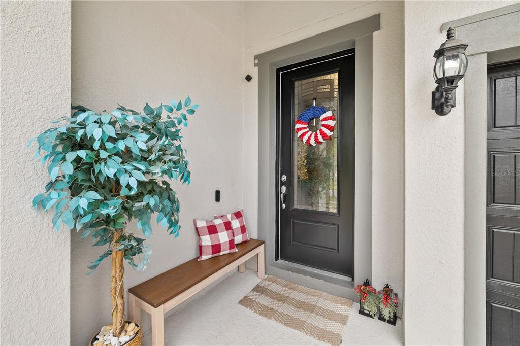 A front porch features a black door, a wooden bench with plaid pillows, and a plant — 9373 ROYAL ESTATES BOULEVARD, ORLANDO, FL