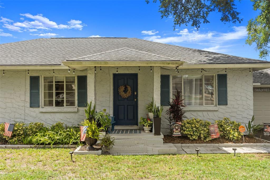 A single-story house with a textured light-colored facade, dark blue door, and blue shutters — 920 ALICIA AVENUE, TAMPA, FL