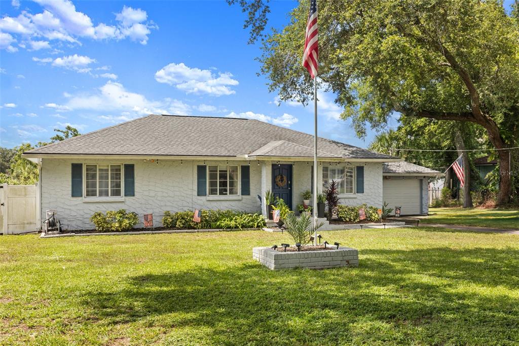 A single-story white brick house with blue shutters and a flag pole in the yard — 920 ALICIA AVENUE, TAMPA, FL