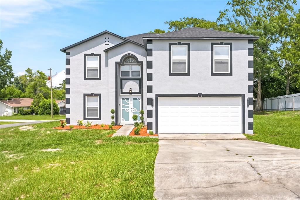 A two-story house with a light gray stucco exterior, dark trim, and a two-car garage — 5292 DENVER AVE, SPRING HILL, FL
