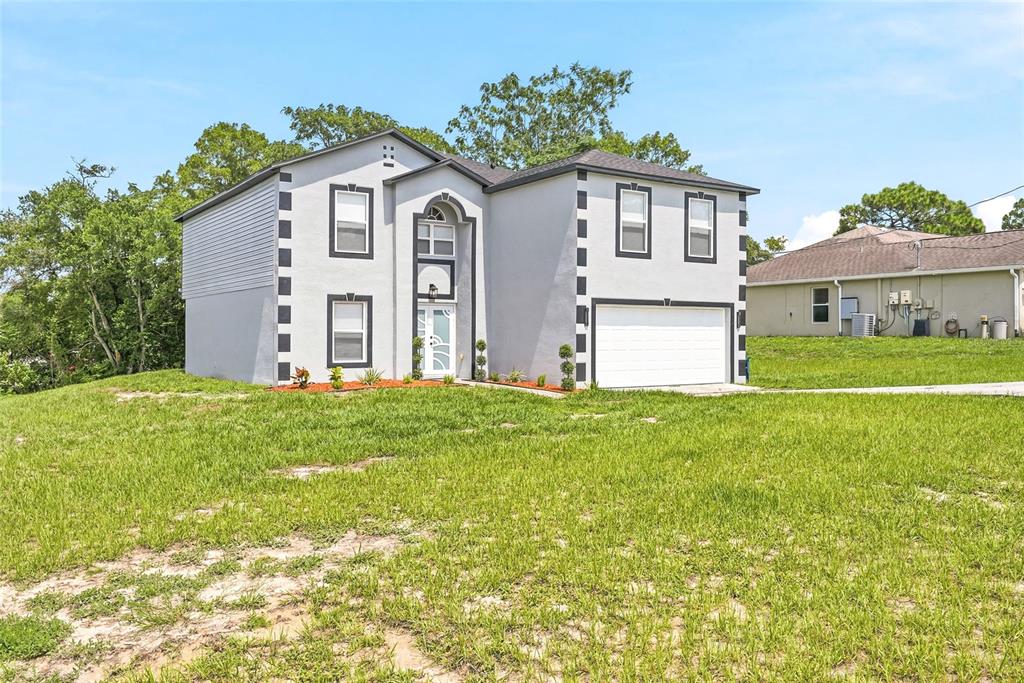 A two-story house with a gray stucco exterior, white trim, and an attached two-car garage — 5292 DENVER AVE, SPRING HILL, FL