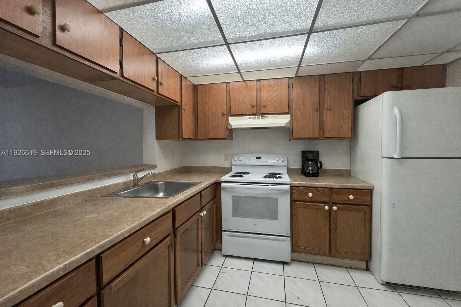 A kitchen features wood cabinets, laminate countertops, white appliances, and a tiled floor — 19701 SW 114th Ave # 14, Miami FL 33157, MIAMI, FL