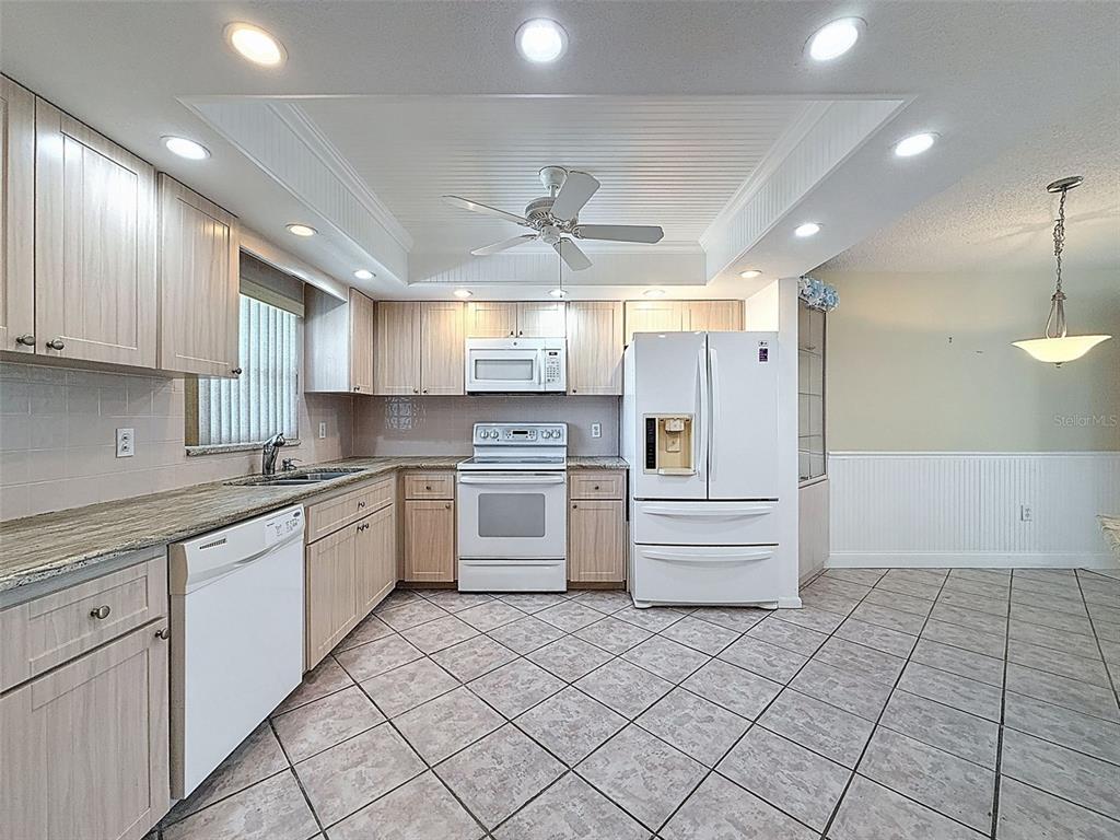 A kitchen features light wood cabinets, white appliances, tile flooring, and a tray ceiling — 4550 COVE CIRCLE UNIT 507, ST PETERSBURG, FL
