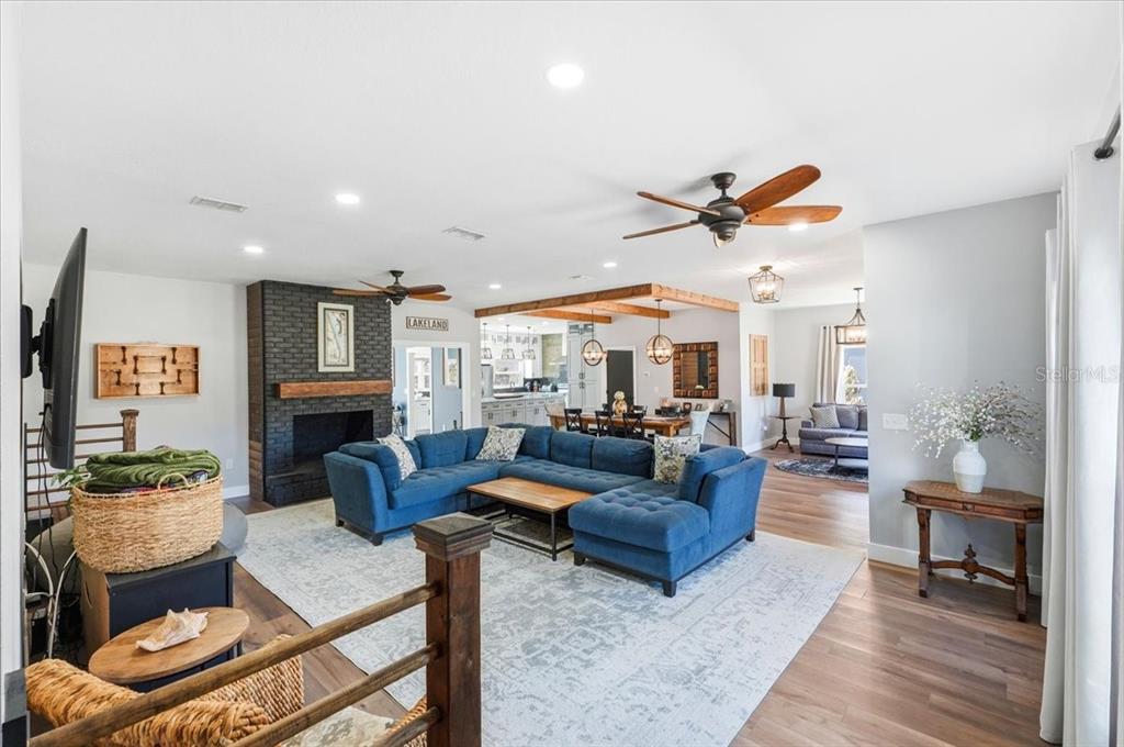 A living room features a blue sectional sofa, a black brick fireplace, and wood flooring — 5225 GLENMORE DRIVE, LAKELAND, FL