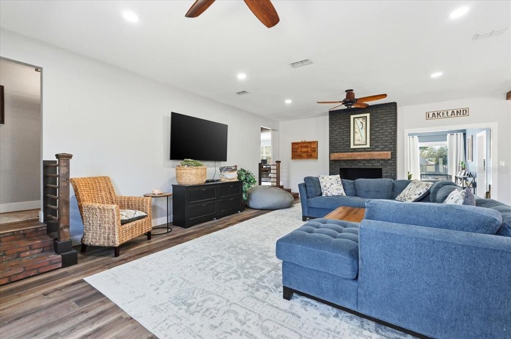 A living room features a blue sectional sofa, a brick fireplace, and a wicker chair — 5225 GLENMORE DRIVE, LAKELAND, FL