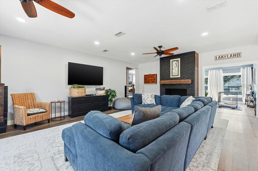 A living room features a blue sectional sofa, a black fireplace, and a television — 5225 GLENMORE DRIVE, LAKELAND, FL