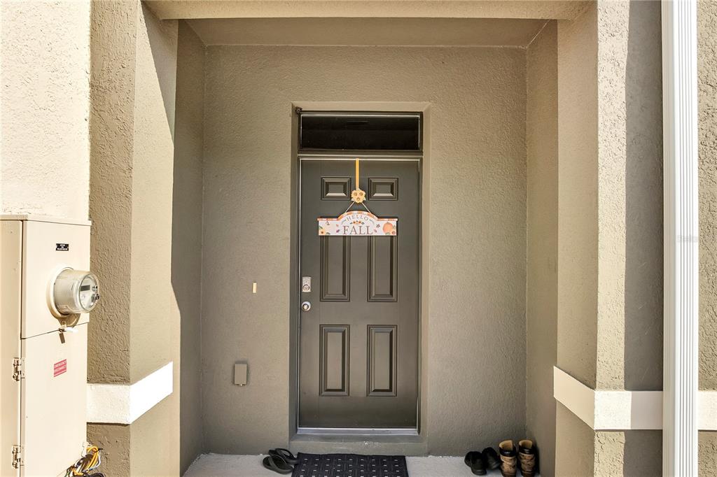 A dark front door with a fall sign is set within a recessed exterior entryway — 1394 YELLOW FINCH DRIVE, DAVENPORT, FL