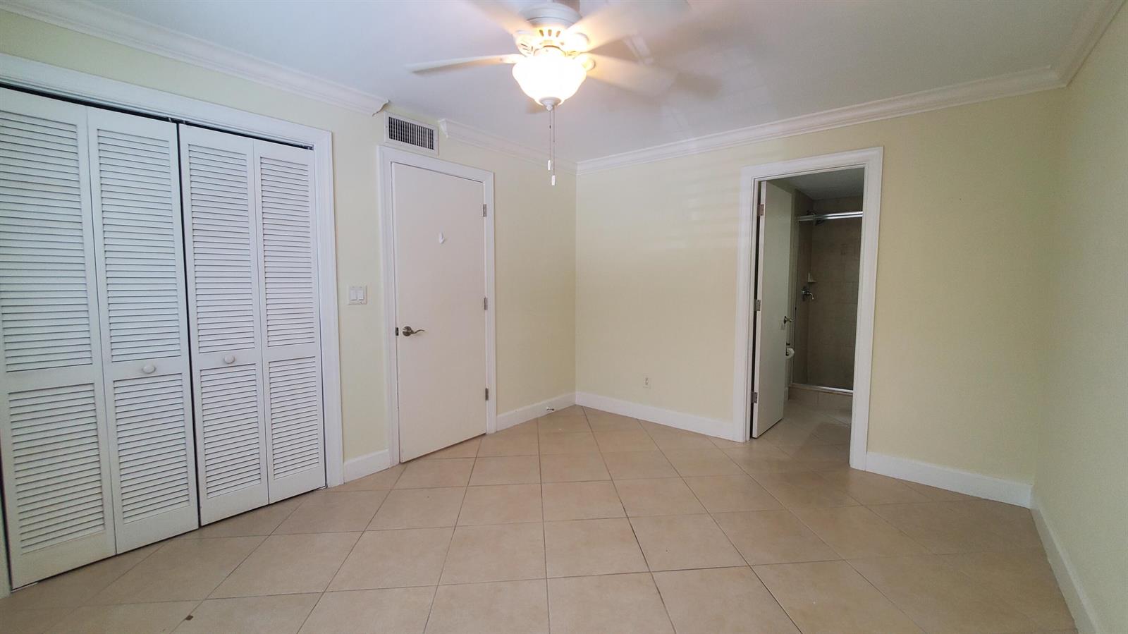 A bedroom with tile flooring, a ceiling fan, louvered closet doors, and an attached bathroom — 1727 HIGHWAY A1A Highway # 106, Vero Beach FL 32963, VERO BEACH, FL