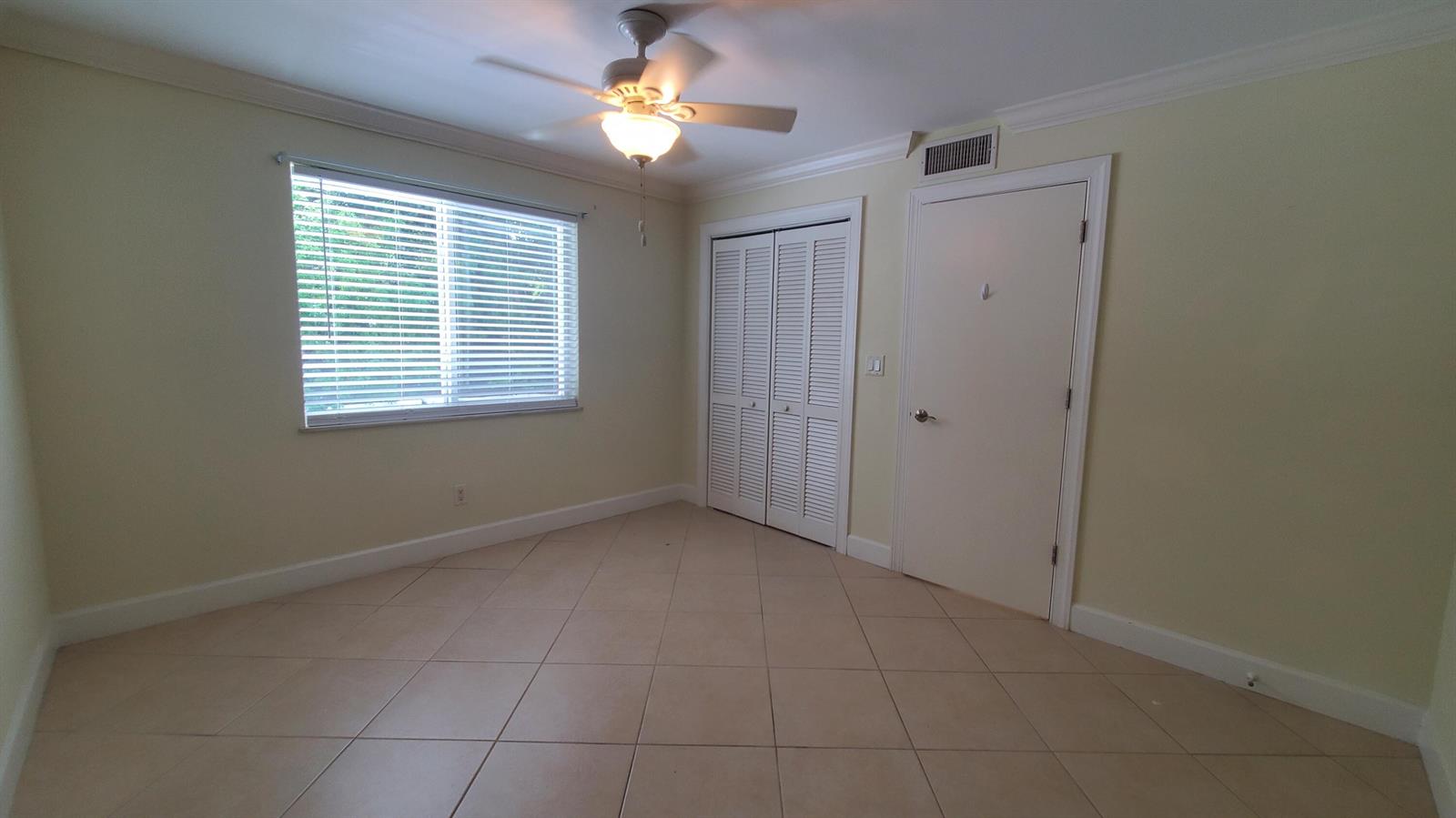 An empty bedroom features light-colored walls, tile flooring, a ceiling fan, and white doors — 1727 HIGHWAY A1A Highway # 106, Vero Beach FL 32963, VERO BEACH, FL
