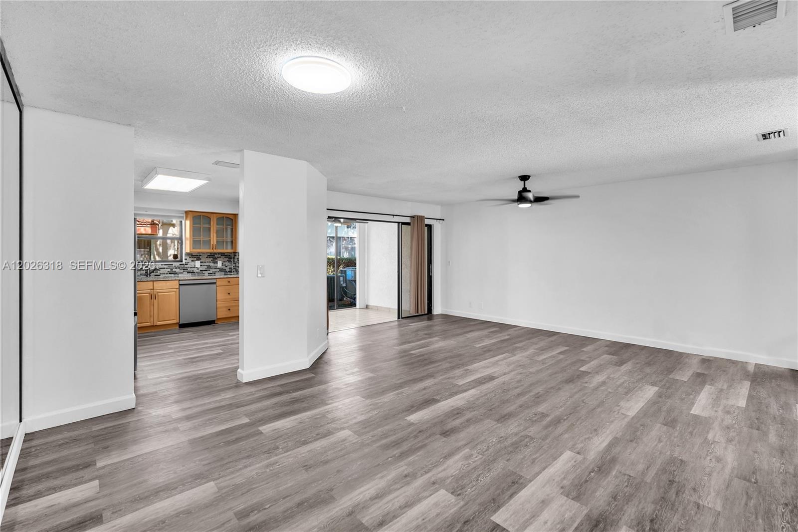 An open-concept living area features wood-look flooring, a ceiling fan, and an adjacent kitchen — 3405 Emerald Oaks Dr # 00, Hollywood FL 33021, HOLLYWOOD, FL