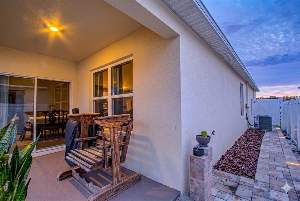 A covered patio features a wooden swing, a sliding glass door, and a stone walkway — 1979 CACUTTA WAY, KISSIMMEE, FL