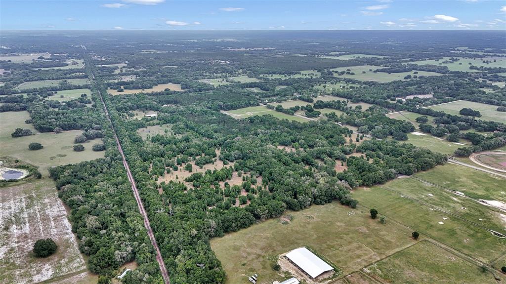 An aerial view shows a large rural property with pastures, wooded areas, and a barn — 650 NE 200TH AVENUE, WILLISTON, FL