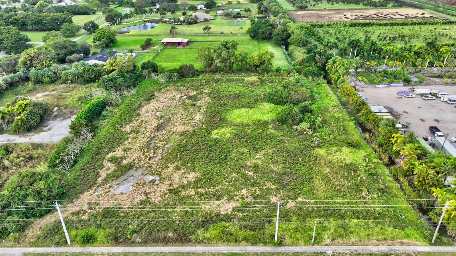 An aerial view shows a large, rectangular, overgrown vacant lot bordered by trees and roads — 15445 S State Road 7 Road, Delray Beach FL 33446, DELRAY BEACH, FL
