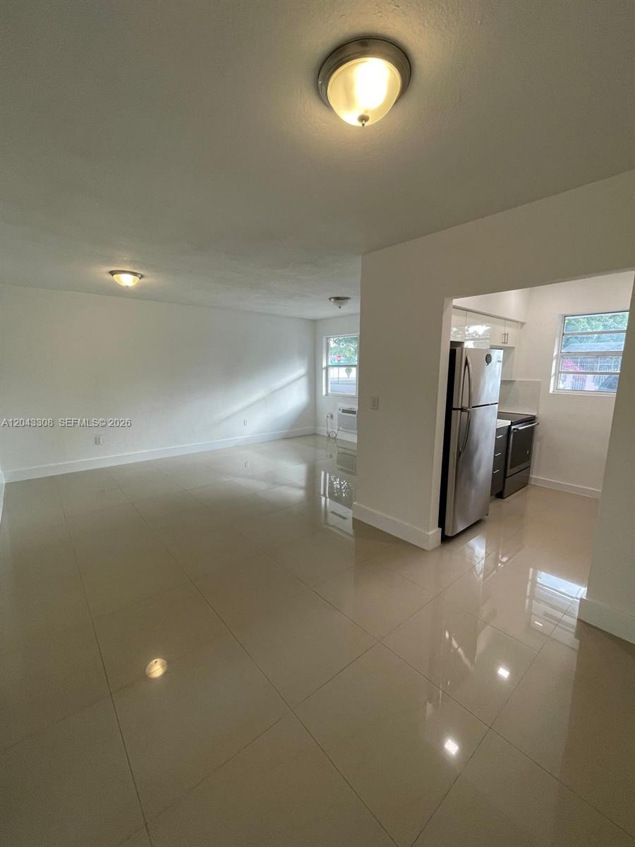 A bright, open-concept living area features light-colored tile flooring and an adjacent kitchen — MIAMI, FL