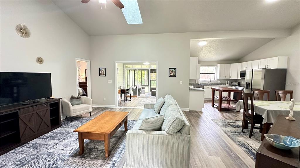 An open-concept living room features a sofa, coffee table, and kitchen with white cabinetry — 782 PINE SHORES CIRCLE, NEW SMYRNA BEACH, FL