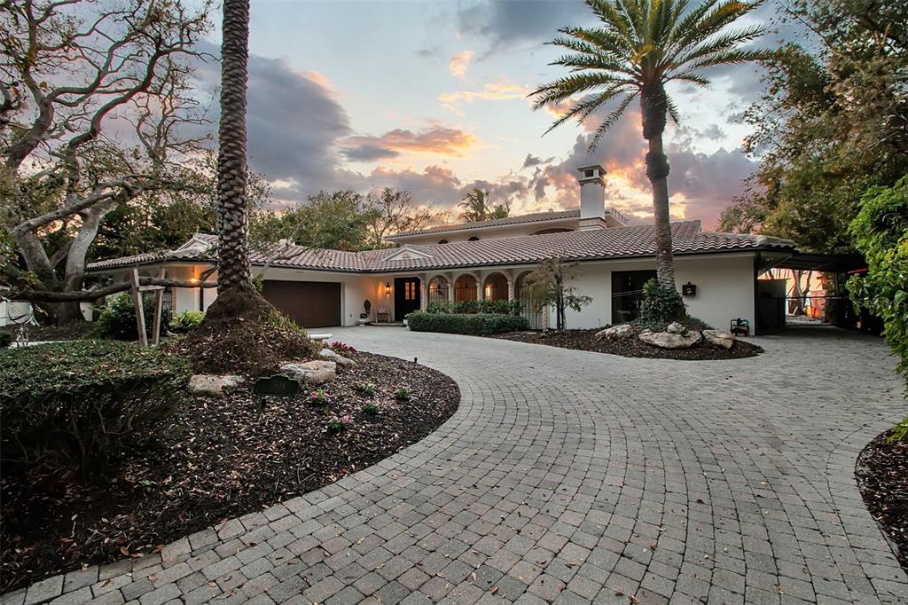 A single-story house with a tiled roof and a curved paver driveway at sunset — 1504 S LODGE DRIVE, SARASOTA, FL