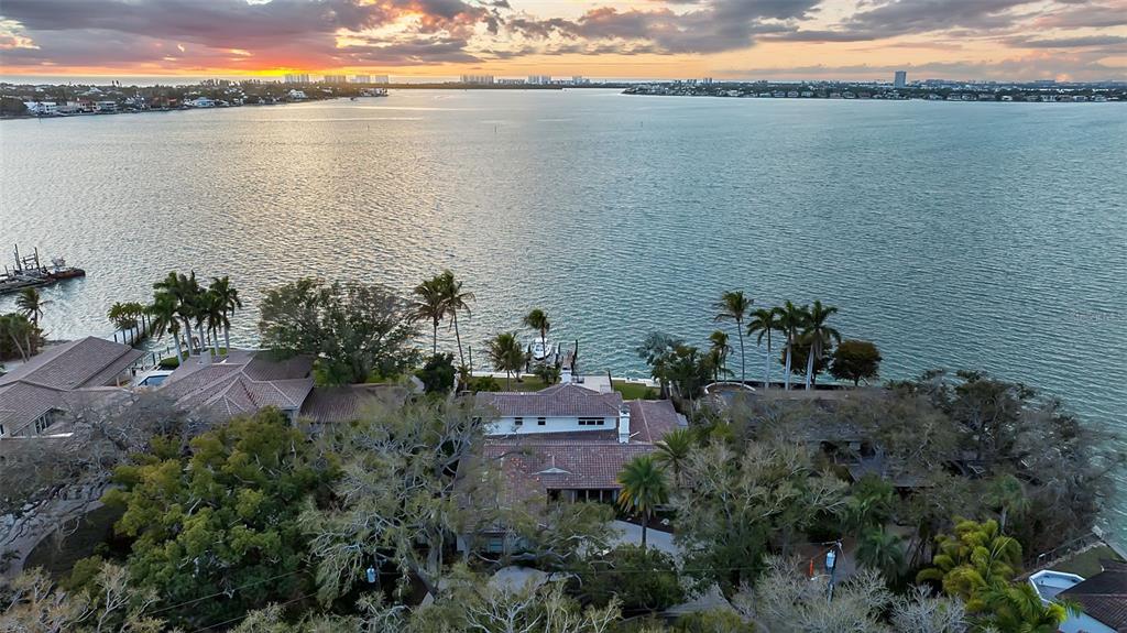 An aerial view shows waterfront homes with tiled roofs surrounded by trees along a bay — 1504 S LODGE DRIVE, SARASOTA, FL
