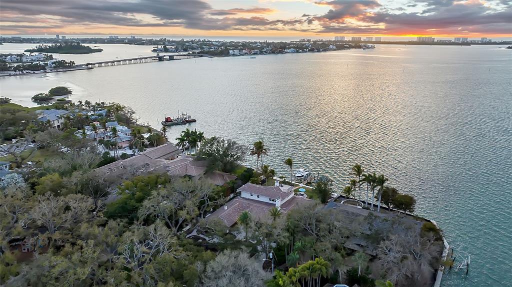 An aerial view shows waterfront houses surrounded by trees along a bay at sunset — 1504 S LODGE DRIVE, SARASOTA, FL